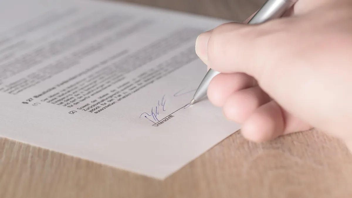 Hand unterschreibt einen Vertrag mit Kugelschreiber