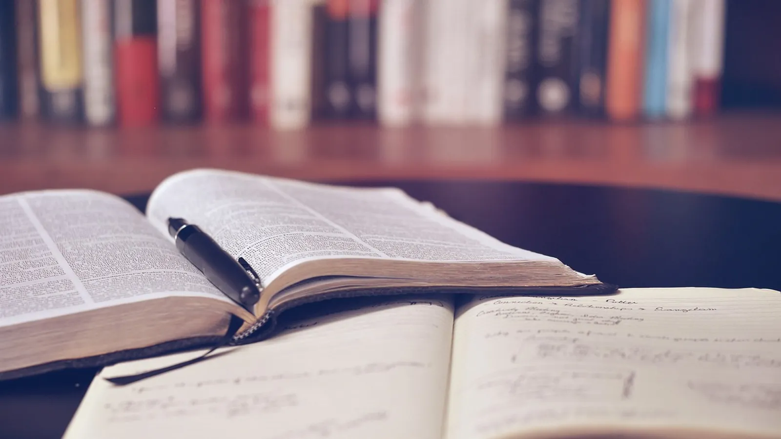 Aufgeschlagenes Buch mit Stift in einer Bibliothek